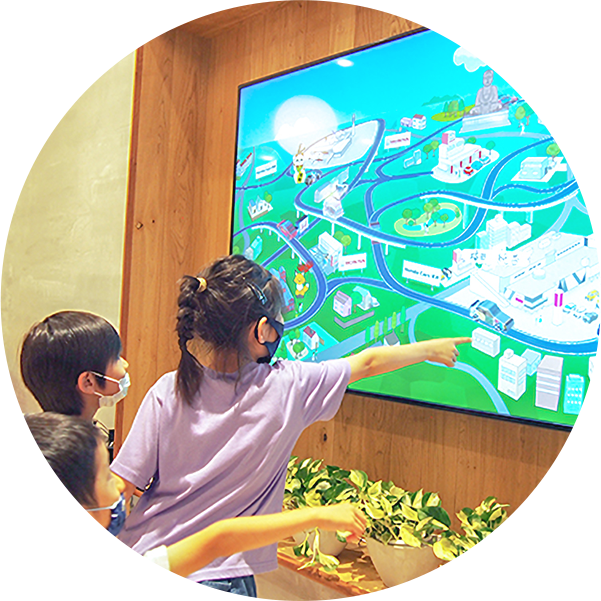子どもたちが大画面に映るカラフルなマップイラストを指さす様子